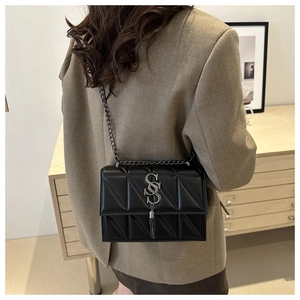 Detail of black quilted leather shoulder bag with metallic SS logo and chain fringe strap
