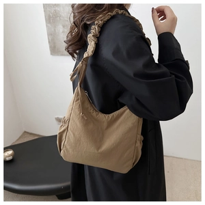 Detail of khaki scrunchie shoulder strap and side elastic pocket on tote bag
