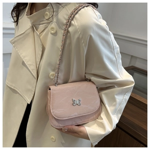 Détail du sac bandoulière rose motif marbre avec fermoir papillon sur manteau beige