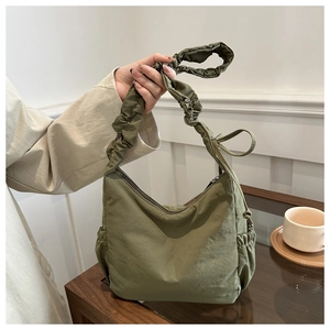 Detail of green ruched shoulder strap and drawstring nylon fabric on underarm tote bag