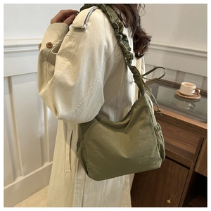 Detail of olive green nylon tote bag featuring scrunchie strap and pleated texture