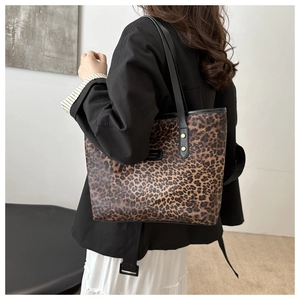 Detailed view of leopard print tote bag with black shoulder straps and brand logo patch