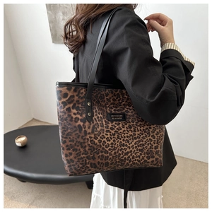 Detail of trendy leopard print tote bag featuring black leather logo and sleek shoulder straps