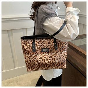 Close-up of leopard print tote bag with black handles and golden rivet hardware detail