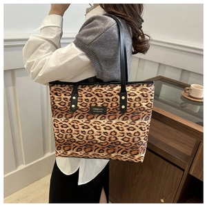 Detail of leopard print tote bag featuring black leather straps and universe label