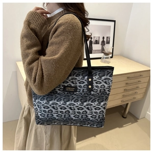Detail of grey leopard print tote bag with black shoulder straps and brand label