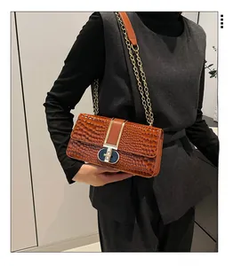 Detail of retro brown faux crocodile skin texture and gold metal clasp on a shoulder bag