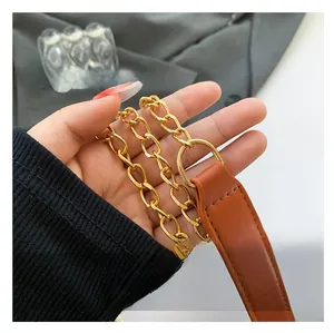 Detail of detachable shoulder strap with gold chain links and brown leather padding