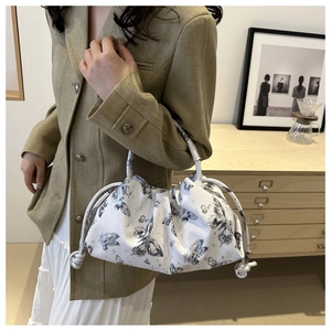 Detail of white drawstring bucket bag with black butterfly print and knotted side straps