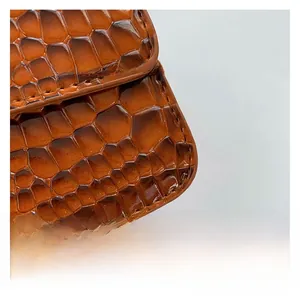 Detailed close-up of glossy caramel brown crocodile embossed leather with fine stitching