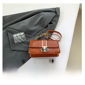Detail of orange-brown crocodile pattern shoulder bag with golden chain and metal buckle