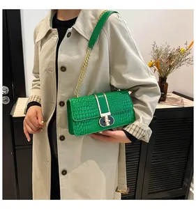 Close-up of vibrant green faux crocodile shoulder bag with golden metallic clasp and chain