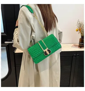 Detail of emerald green crocodile embossed shoulder bag with gold chain and buckle