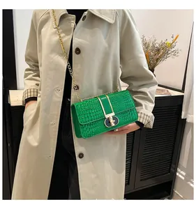Detail of bright green crocodile embossed shoulder bag with gold chain and metal lock