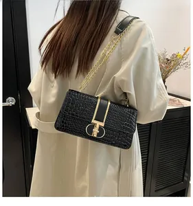 Detail of black crocodile pattern leather shoulder bag with elegant gold metal clasp