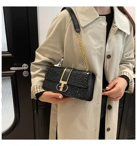 Detailed view of black crocodile pattern shoulder bag with a gold D-buckle hardware