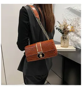 Close-up of glossy brown crocodile pattern handbag with gold T-shaped metal buckle detail