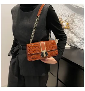 Brown crocodile pattern shoulder bag with gold chain strap shown on model for size comparison