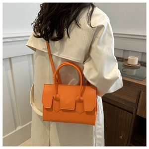 Close-up of vibrant orange handbag worn with a beige trench coat for a stylish fall look