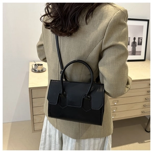 Detail of a black structured crossbody square bag styled with an elegant khaki blazer
