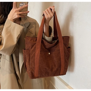 Detail of a brown corduroy tote bag featuring multiple pockets and a retro winter style