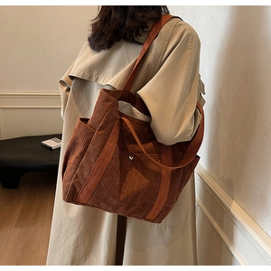 Detail of brown corduroy tote bag showing vertical texture and side pocket on trench coat