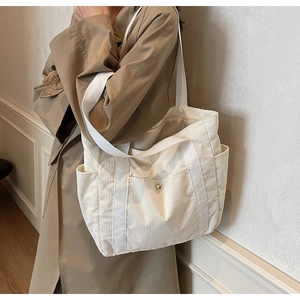 Detail view of corduroy tote bag featuring a front pocket with a gold metallic buckle