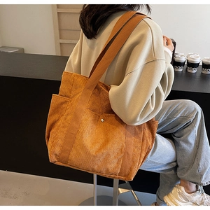 Detail of corduroy tote bag showing large capacity texture and shoulder strap on model