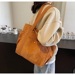 Close-up of orange corduroy tote bag with wide strap and exterior metal buckle pocket
