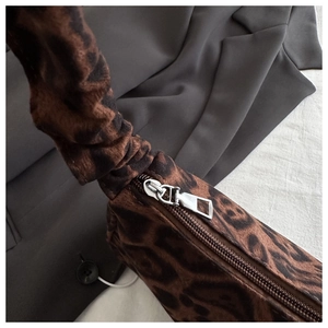 Detail of leopard print handbag featuring a ruched handle and silver metal zipper