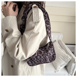 On-shoulder view of purple leopard print mini bag with ruched strap and silver zipper