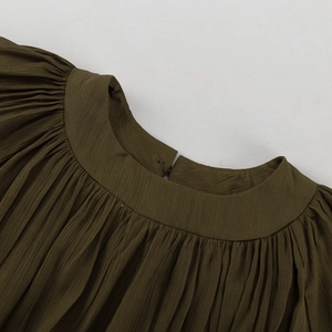 Gros plan du col plissé de la robe vert olive avec détail de fermeture à bouton