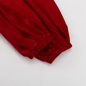 Détail de la manche d'une robe en satin rouge avec poignet élastique et plis élégants