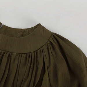 Gros plan du col montant et des plis fins sur la robe en mousseline vert olive foncé