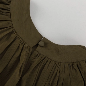 Détail d'une robe plissée vert olive avec fermeture à bouton recouvert au col arrière