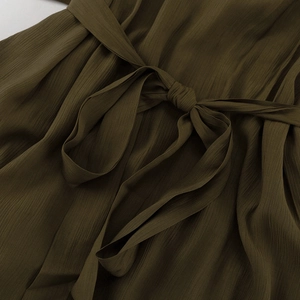 Détail du tissu plissé vert olive avec une taille cintrée et un nœud assorti