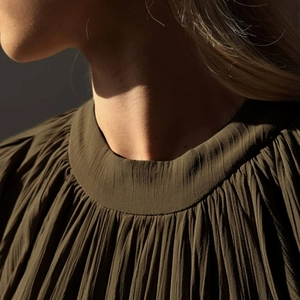 Gros plan d'une robe plissée vert olive avec une encolure ronde élégante et chic