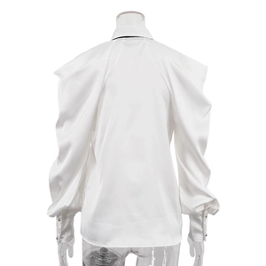 Dettaglio di camicia in raso bianco con ampie maniche a lanterna e bottoni sui polsini