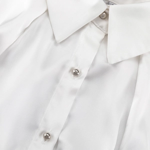 Dettaglio camicia in raso bianco con tessuto lucido e bottoni sferici in argento
