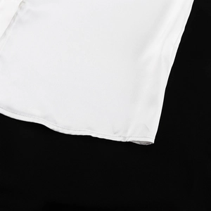 Vista macro dell'orlo di camicia bianca in tessuto con cuciture precise su sfondo nero