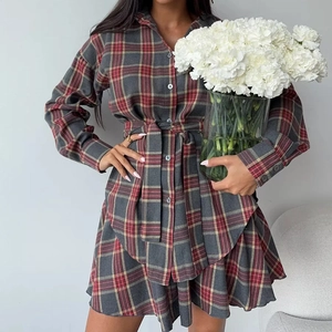Détail de la robe chemisier à carreaux rouge et gris avec ceinture et jupe plissée