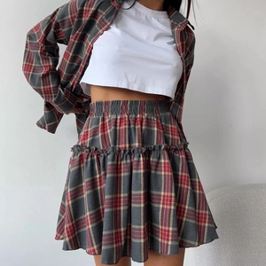 Détail d'un ensemble chemise à carreaux rouge et gris avec mini-jupe plissée à volants