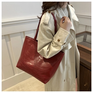 Détail du sac cabas rouge avec une texture gaufrée unique sur la surface en cuir
