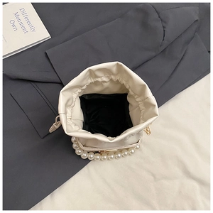 Detailed top view of cream drawstring bucket bag featuring elegant faux pearl handle and black lining
