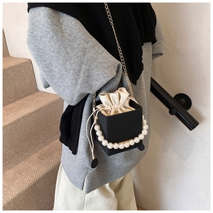 Detail of black pearl bucket bag with gold chain strap and cream drawstring liner