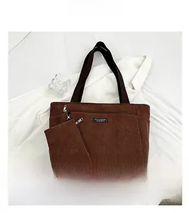 Dettaglio della borsa tote in velluto marrone con trama verticale, tasca a zip e mini pochette