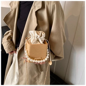 Detail of khaki woven box bag with pearl handle and silk drawstring bag interior