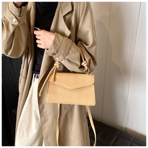 Dettaglio della borsa squadrata intrecciata beige con manico a nodo e trama elegante