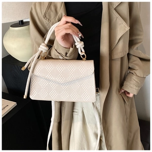 Dettaglio elegante borsa in pelle intrecciata crema con manico a nodo e fibbie dorate