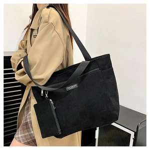 Dettaglio della borsa tote in velluto a coste nera con etichetta FASHION e astuccio